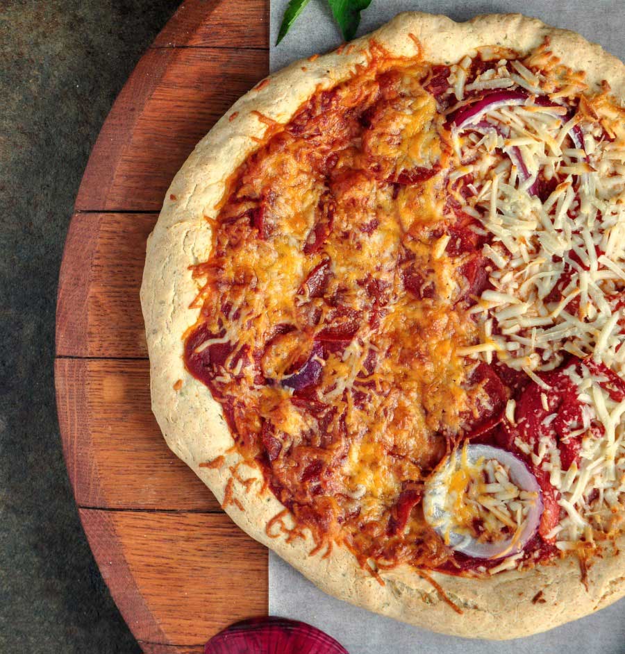 Golden gluten-free pizza made with gfJules crust mix served on a wooden board
